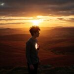 A young man standing on a cliff overlooking a beautiful landscape, with a glowing light emanating from his heart. reclaiming paradise, abundance, financial freedom, personal growth, spiritual enlightenment, mindfulness, meditation, yoga, positive thinking, gratitude, compassion, generosity, service, community, connection, purpose, meaning, happiness, joy, peace, love